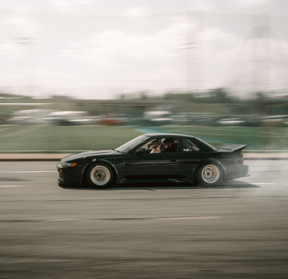 Das bild zeigt einen tiefergelegten weißen Golf 7 GTI mit großen Felgen, dieser steht auf einer Plattform und im Hintergrund ist eine Stadt zu sehen das Bild hat ein warmes Licht