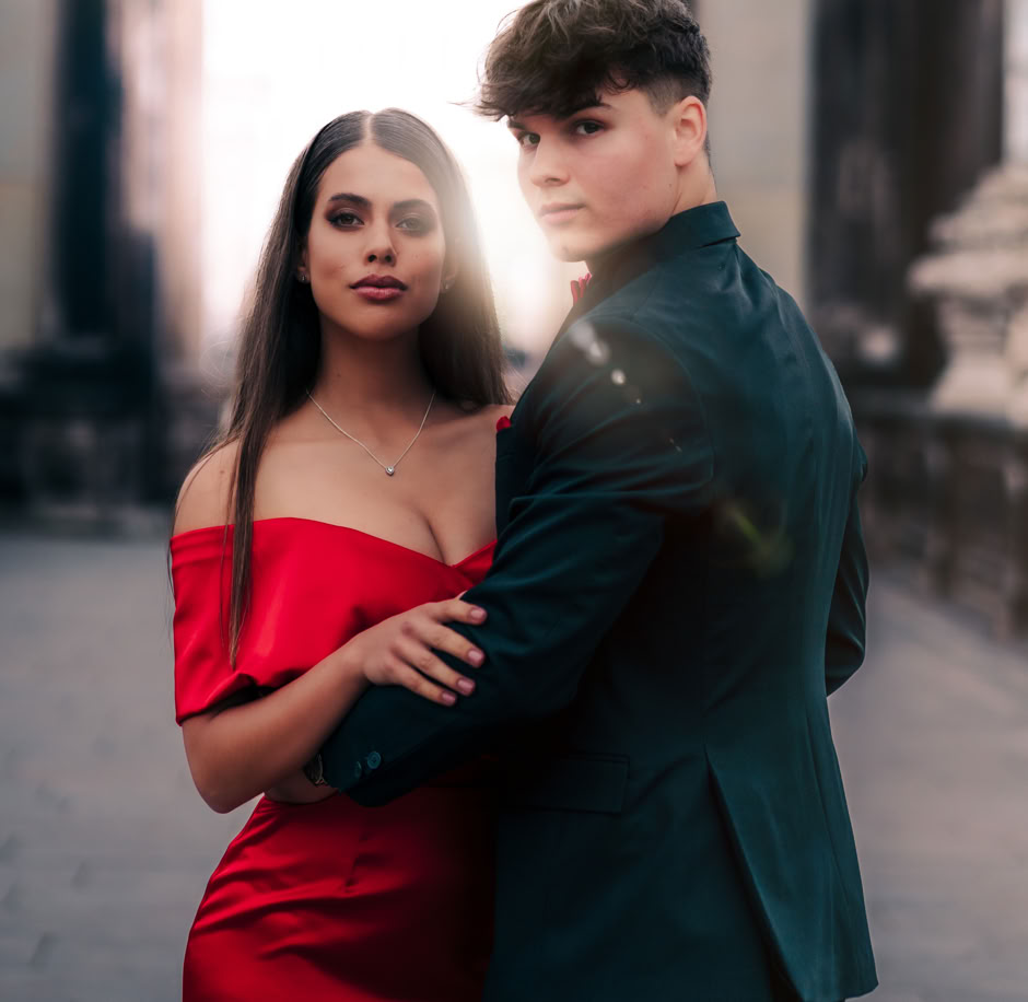 Die Person wurde vor einer Statue des Dresdner Zwingers fotografiert, sie nimmt ihre Haare zurück und hat einen freundlichen Gesichtsausdruck mit geschlossenen Augen